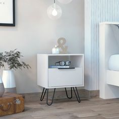 a white cabinet with some glasses on it next to a suitcase and a plant in a vase