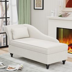 a white chaise lounge chair sitting in front of a fire place