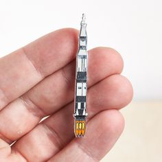 a miniature model of a rocket ship in the palm of someone's left hand