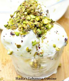 two desserts with pistachio and yogurt on a wooden table next to a spoon