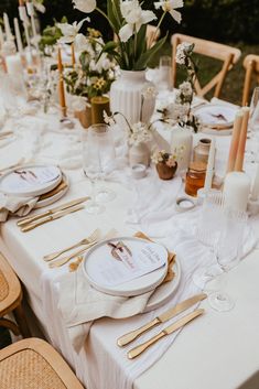 the table is set with white linens and gold place settings