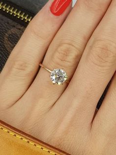 a woman's hand with a ring on it and a red manicured nail