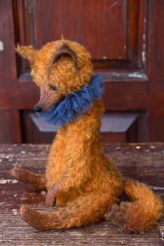 a teddy bear with a blue bow sitting on a wooden table in front of a door