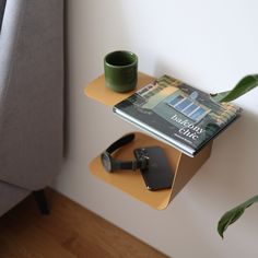 a table with a book, cup and headphones on it next to a couch