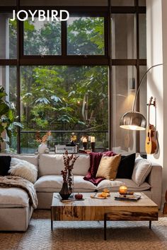 a living room filled with furniture next to a large window covered in plants and trees