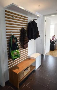 there is a coat rack with two coats hanging on it and a bench in the corner