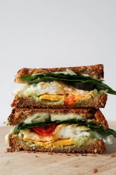 two sandwiches stacked on top of each other with eggs and veggies in them