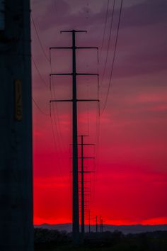 the sun is setting behind power lines and telephone poles