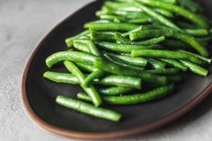 green beans on a black plate sitting on a table