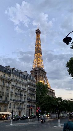 the eiffel tower is lit up at night, with people crossing the street