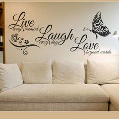 a living room with a couch and wall decals on the walls that say live laugh love