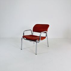 a red chair sitting on top of a white floor next to a black and silver object