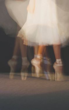 blurry photograph of two women in white dresses and high heeled shoes walking down the street