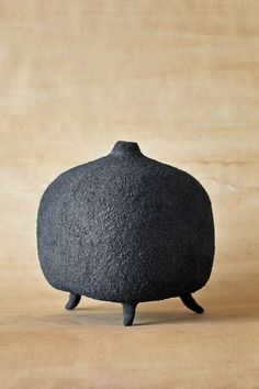 a small black object sitting on top of a wooden table next to a brown wall