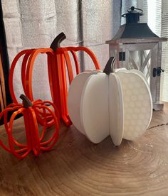 two white pumpkins sitting on top of a wooden table next to a candle holder