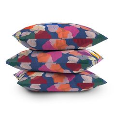 three multicolored pillows stacked on top of each other in front of a white background