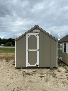 two small sheds sitting in the dirt next to each other