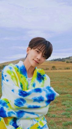 a person standing in a field with a blue and yellow tie dye blanket