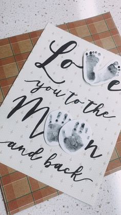 two hand and foot prints on a card that says love you to the moon and back