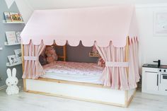 a child's bed with a pink canopy and curtains on the top, in a bedroom