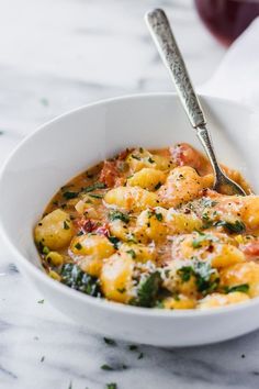 a white bowl filled with macaroni and cheese on top of a marble counter