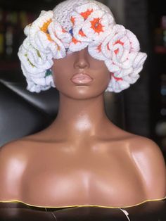 a mannequin wearing a white crochet hat with flowers on it's head