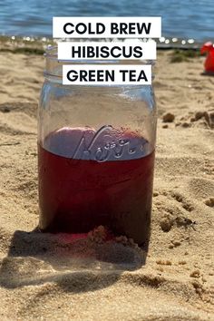 a jar filled with liquid sitting on top of a sandy beach