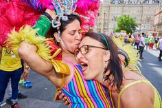 two women kissing each other in the middle of a street with lots of people watching