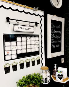 a black and white calendar on a wall next to potted plants