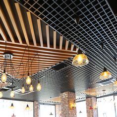 an empty restaurant with lights hanging from the ceiling and brick pillars in front of windows