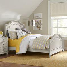 a white bed sitting in a bedroom next to a yellow and white rug on top of a wooden floor