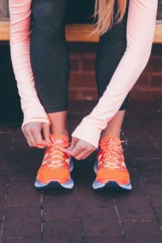 a woman tying up her running shoes on a bench