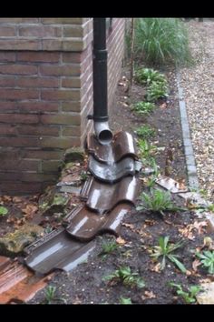 a pipe sticking out of the ground next to a brick wall