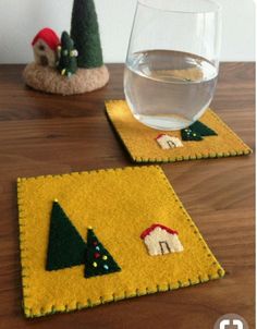 two placemats on a table with a glass of water in the middle and small trees