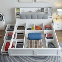 a white bed sitting next to a dresser filled with lots of pillows and other items