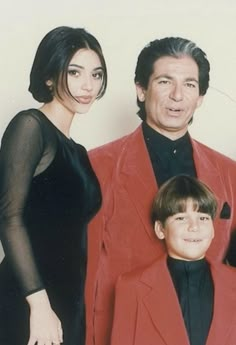 a man and two women standing next to a boy in a red suit with his arm around him