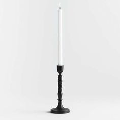 a black candle holder with a single white candle on it's top and bottom