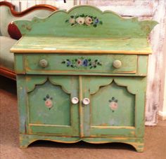 an old green cabinet with flowers painted on it