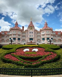 a large building with a face made out of flowers in front of the topiary