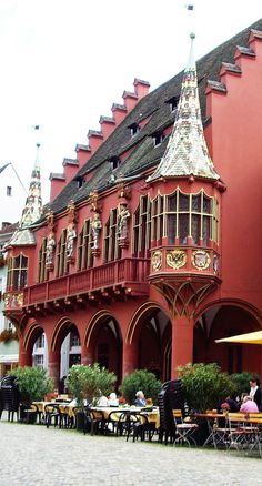 people sitting at tables in front of a red building