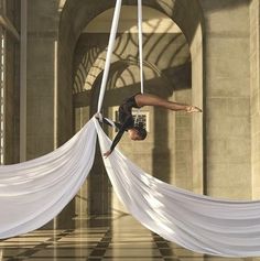 a woman is doing aerial acrobatic tricks in the middle of a building