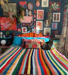 a dog laying on top of a bed covered in colorful blankets and crocheted bedspread