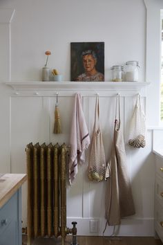 towels hanging on the wall next to a radiator and shelf with pictures above it