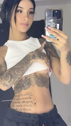 a tattooed woman taking a selfie with her cell phone