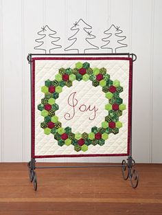 a quilted christmas wreath with the word joy on it, sitting on a table