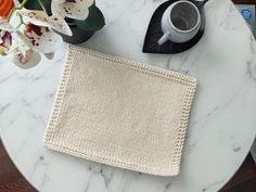 a white table topped with a cup of coffee and a knitted napkin on top of it