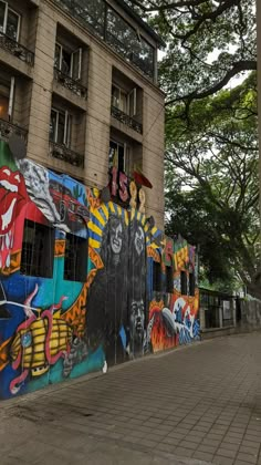 the side of a building with graffiti on it's walls and trees in the background