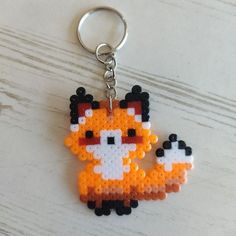 a keychain made to look like an orange fox with black dots on it