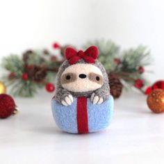 a small stuffed animal with a red bow on its head sitting next to christmas decorations