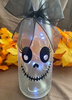 a glass jar with a light up skeleton face on it and a bow around the top